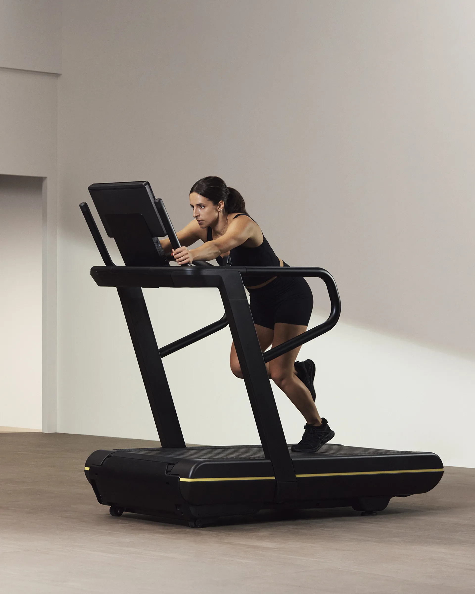 A Life Time Member on a treadmill holding on to the bars.