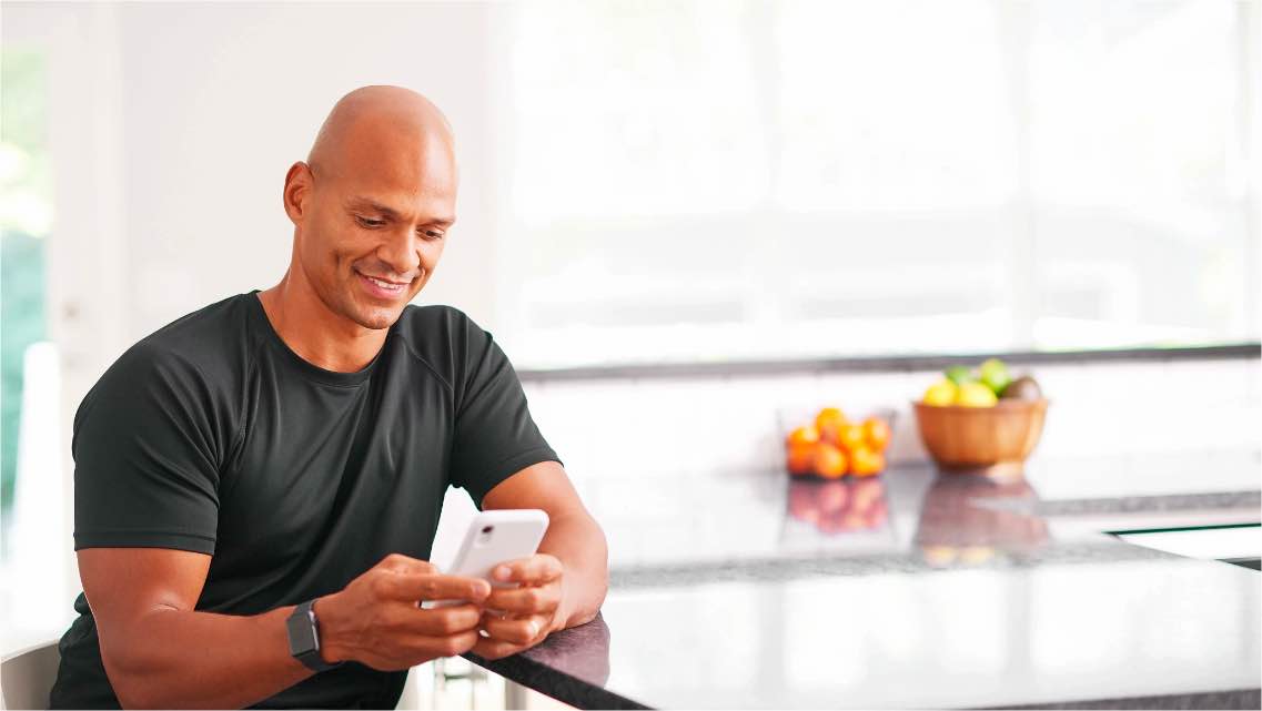 Man sits at a kitchen counter looking at phone